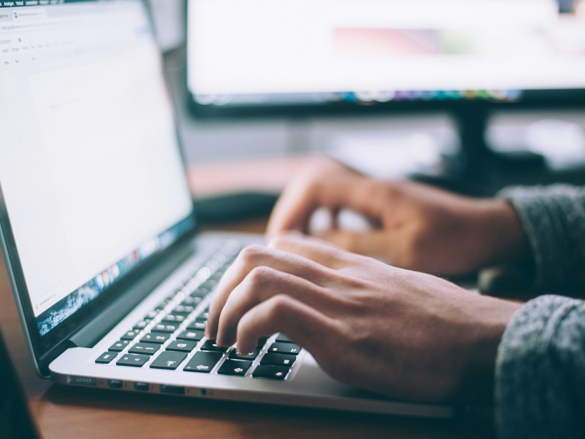 Hands typing on a laptop at a desk